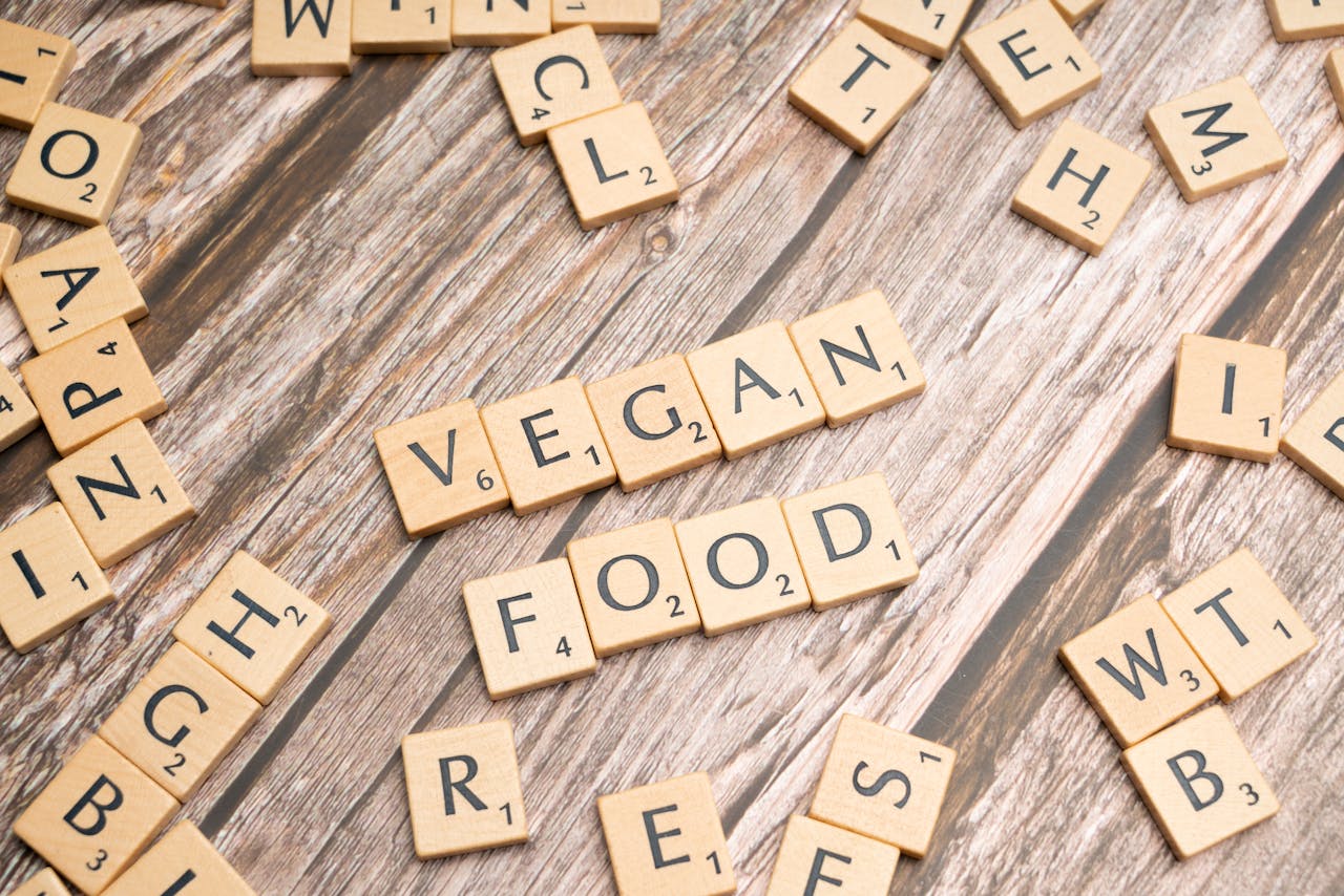 Wooden letter tiles spelling 'vegan food' creatively placed on a wooden surface, highlighting plant-based diet.