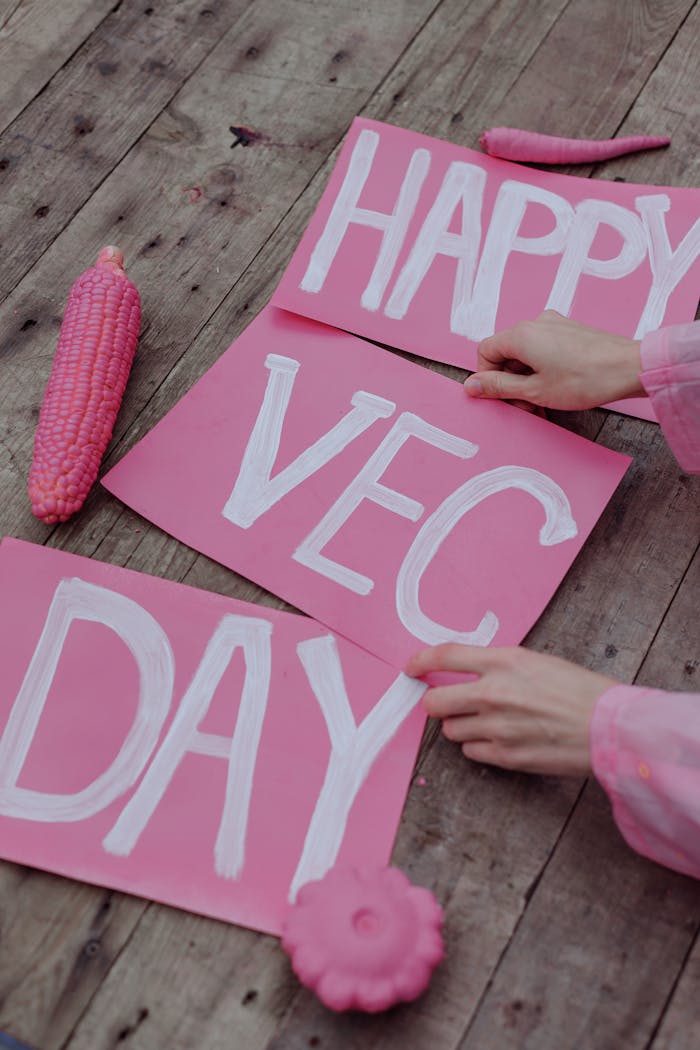 A vibrant pink-themed setup celebrating Vegan Day with painted signs and colorful vegetables.